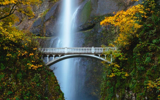 Bridge spanning deep ravine with waterfall in the background