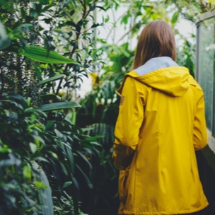 WIllow in yellow jacket facing away from camera, surrounded by plants